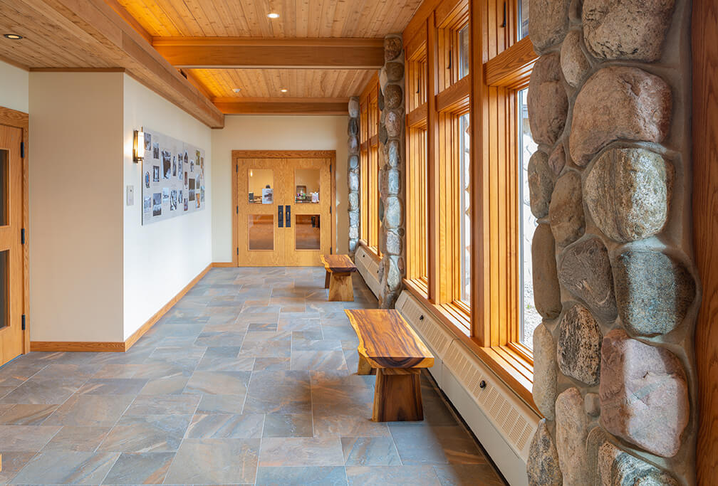 Corridor at Abbey of the Genesee in Piffard NY with dramatic uplighting porcelain tile floor and live edge wood benches
