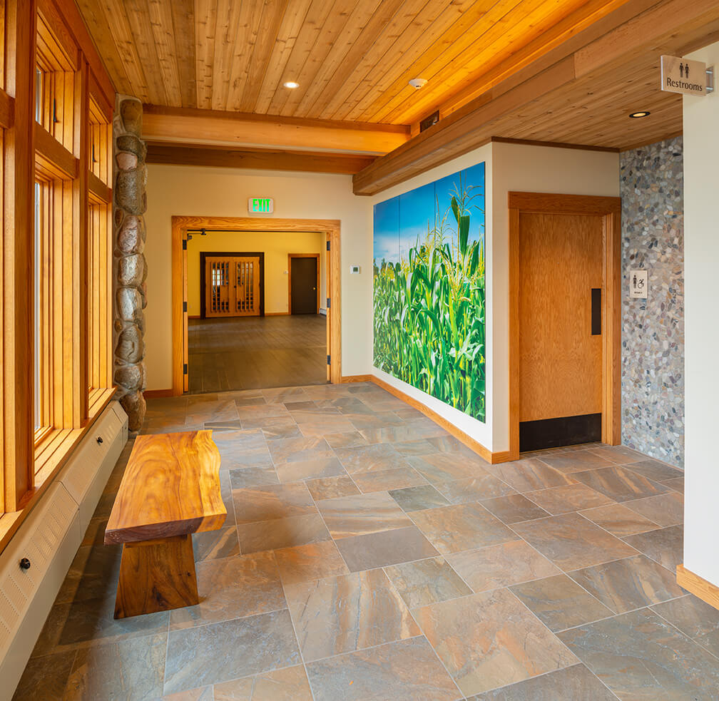 Abbey of the Genesee in Piffard, NY showing corridor with photo mural, stone floor, TakeForm signage and pebble wall tiles