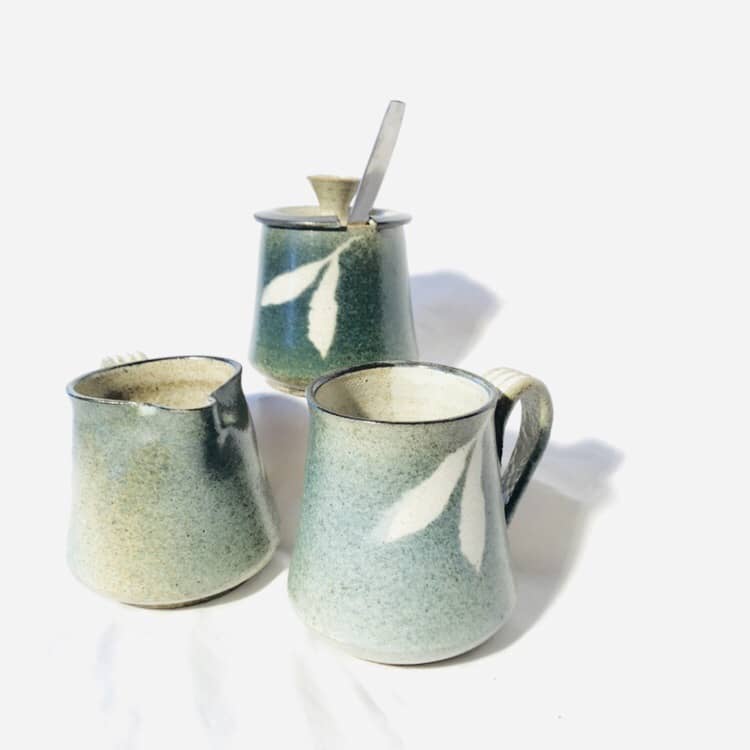 A mug, sugar pot, and cream pitcher with a similar tapered shape. All are glazed with turquoise on top of white.