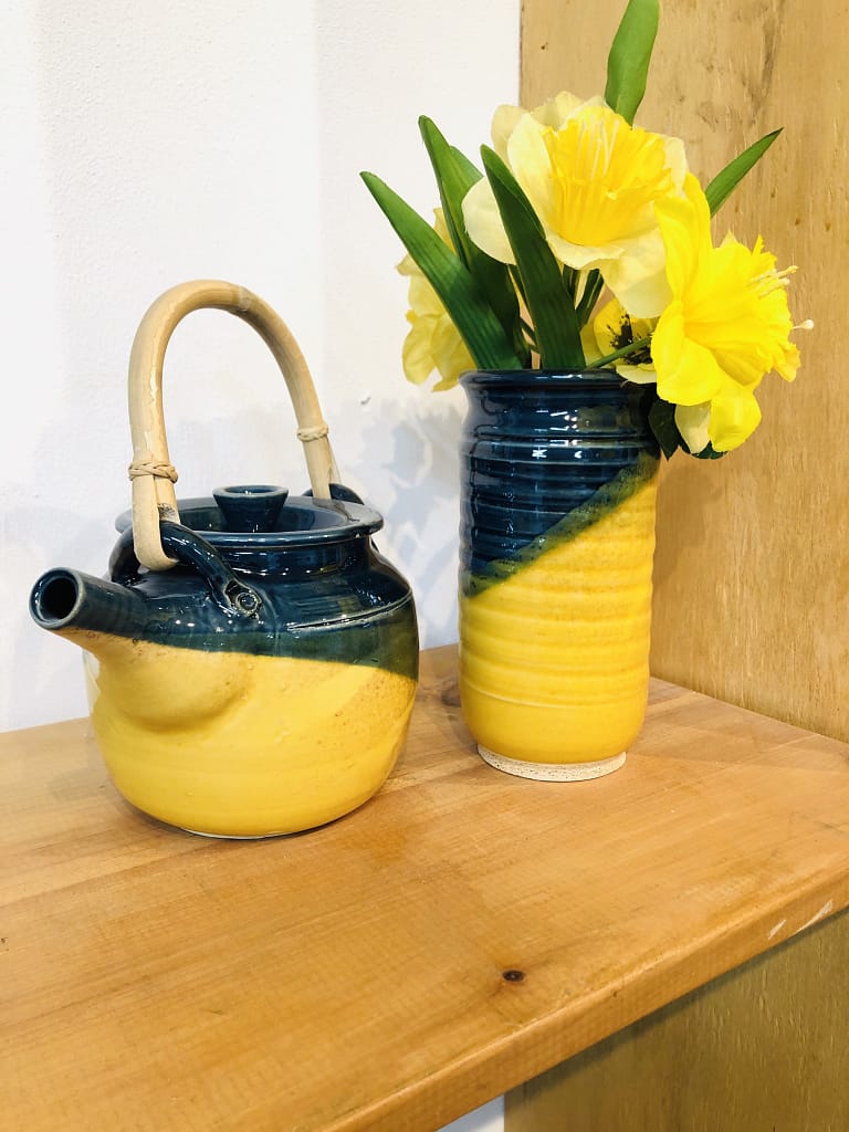 A matching teapot and tall vase in blue and bright yellow glazes