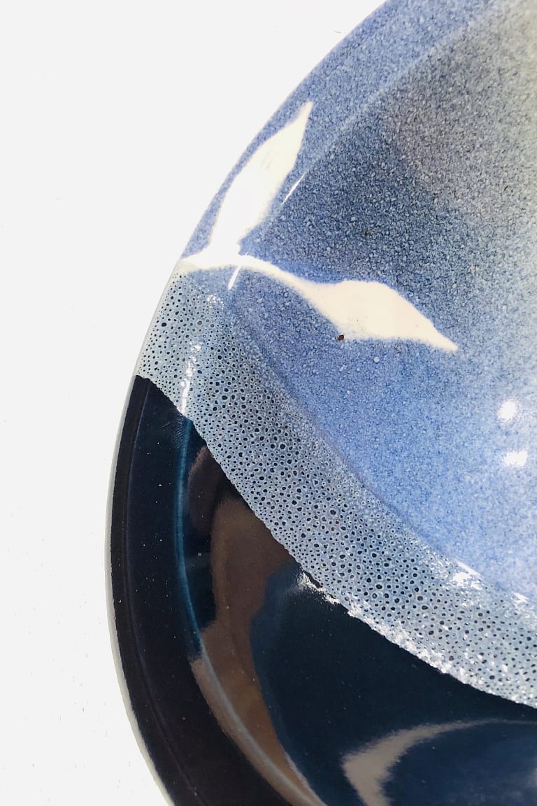 Detailed view of a bowl with layered glazes ranging from very dark to very light blue