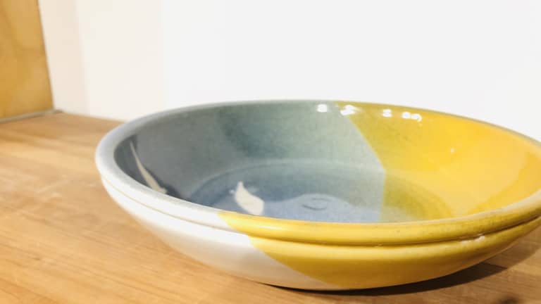 Pofile view of a bowl with blue and bright yellow glaze