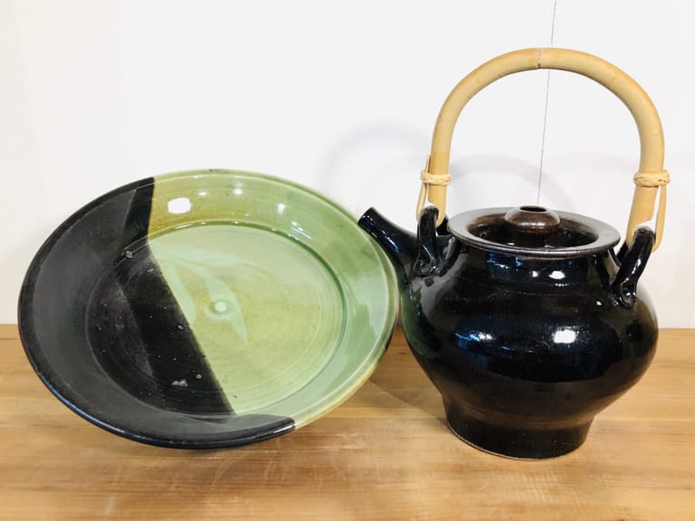 A black-glazed teapot with a platter that is half black and half green