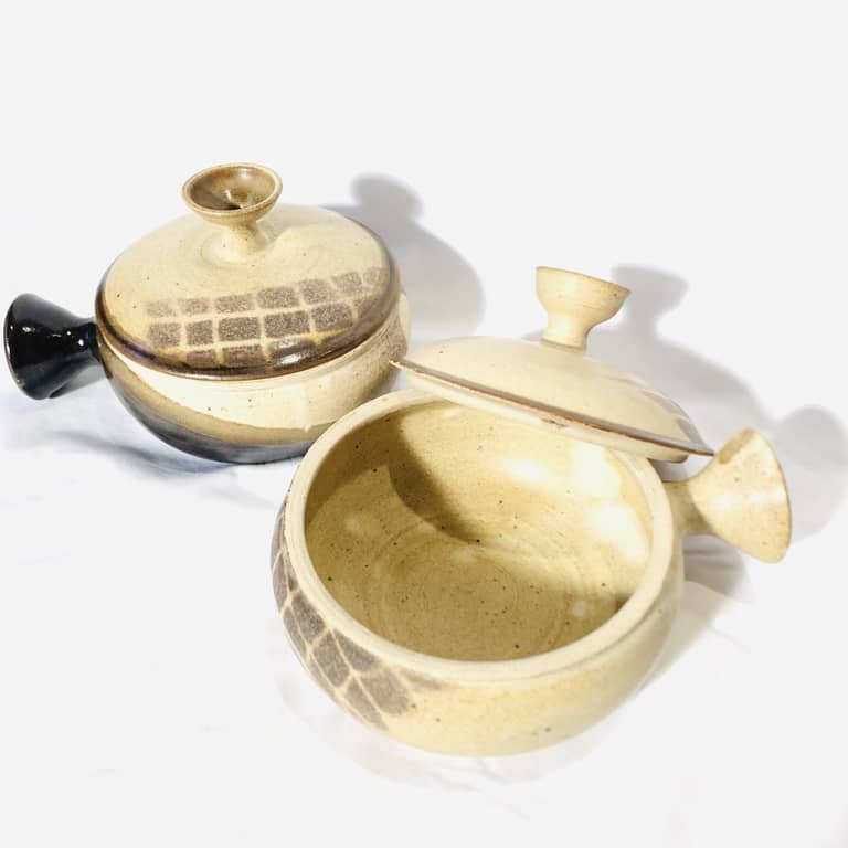 Two small, matching soup crocks with handles and lids in a neutral glaze