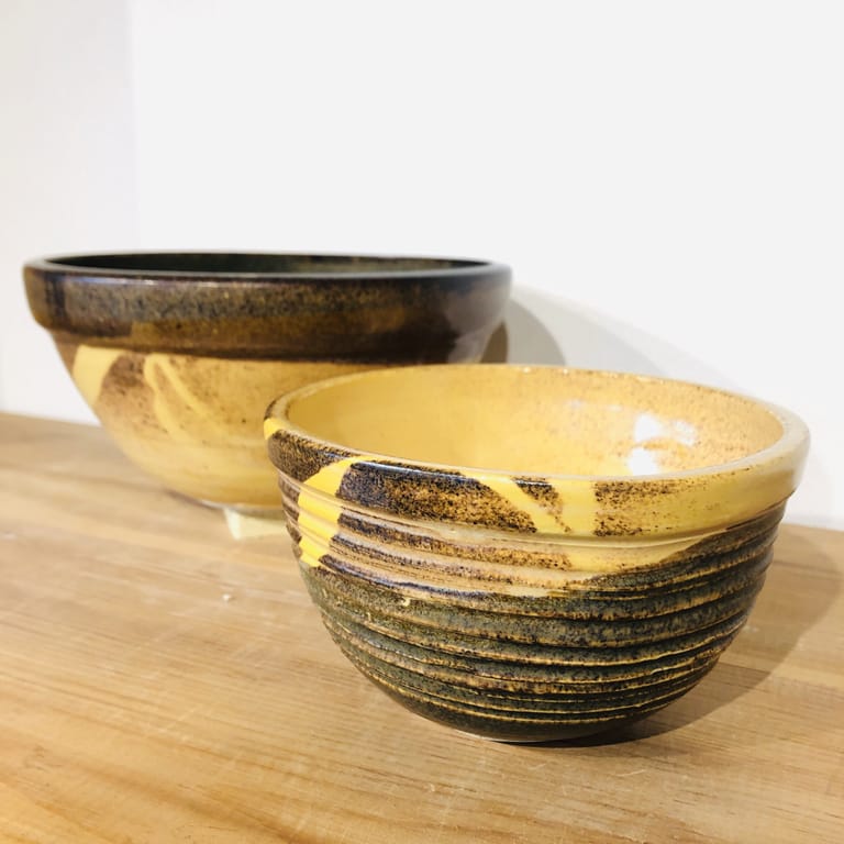 A pair of mixing bowls glazed in temmoku brown, gold, and bright yellow
