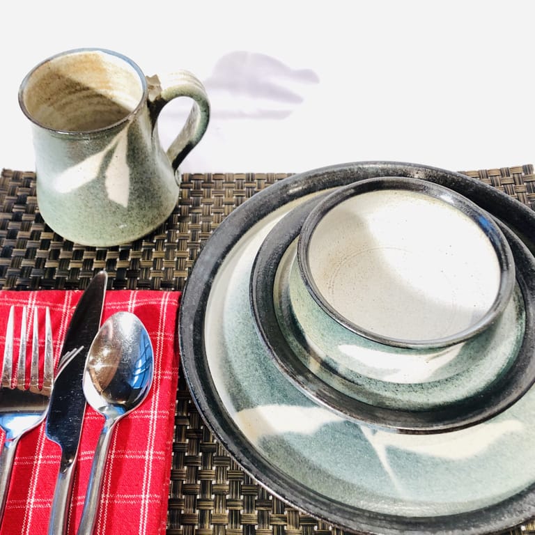 A place setting with dinner and salad plates, a bowl and mug. All are glazed in a neutral turquoise color