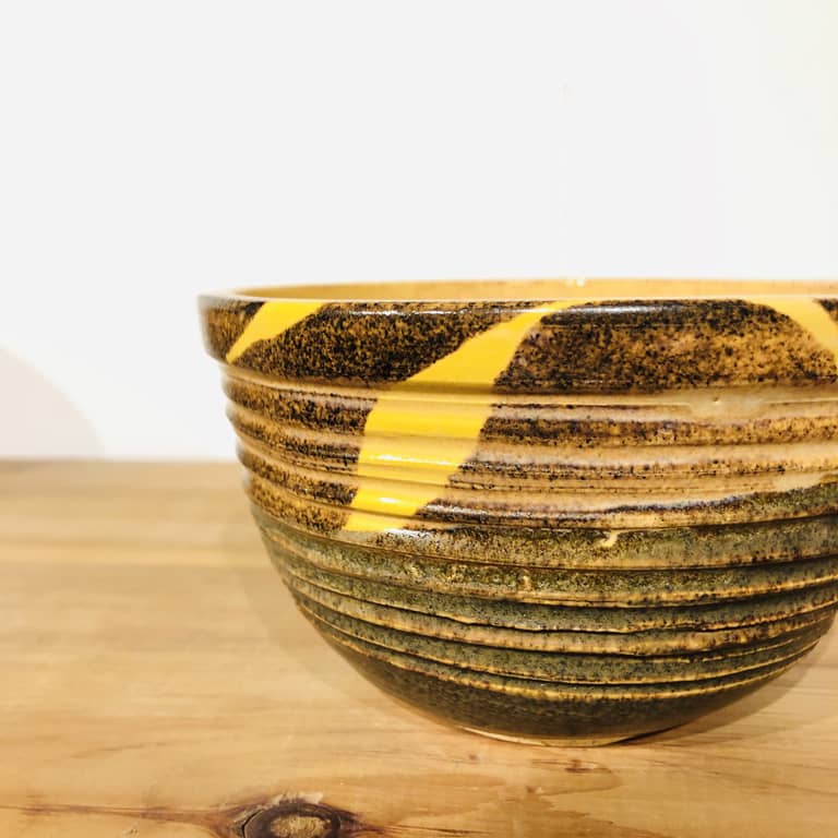 A mixing bowl with textured sides glazed in temmoku brown and bright yellow